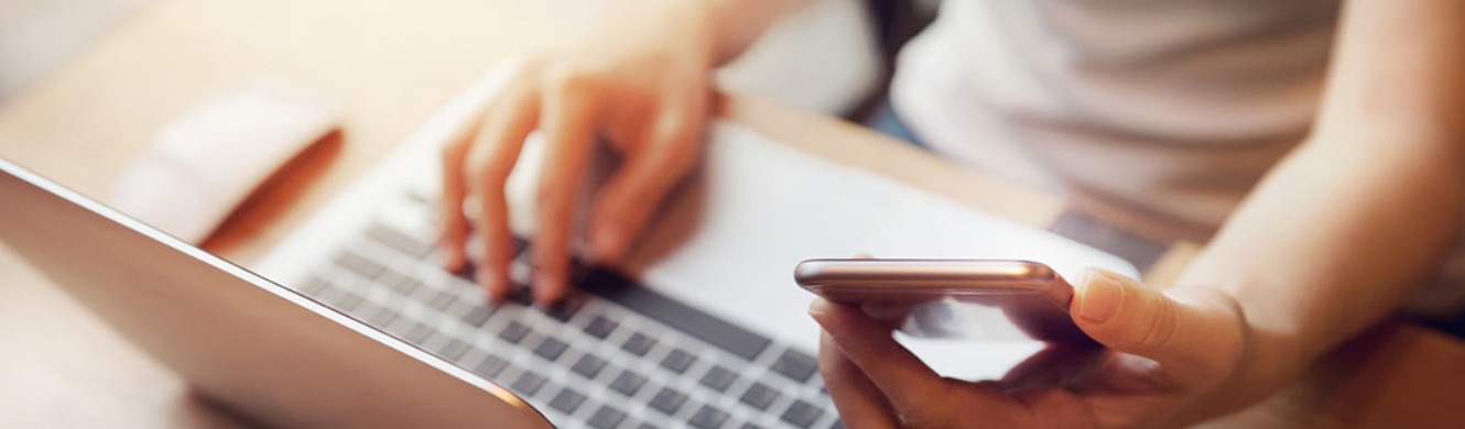 Woman using laptop and cell phone 